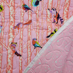 Quilt with colorful bird pattern on a pink background