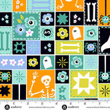 Halloween-themed fabric pattern with squares featuring ghosts, bones, and flowers, measured by a ruler.