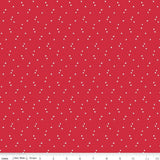 Red fabric with small white star pattern, brand 'Riley Blake Designs' visible
