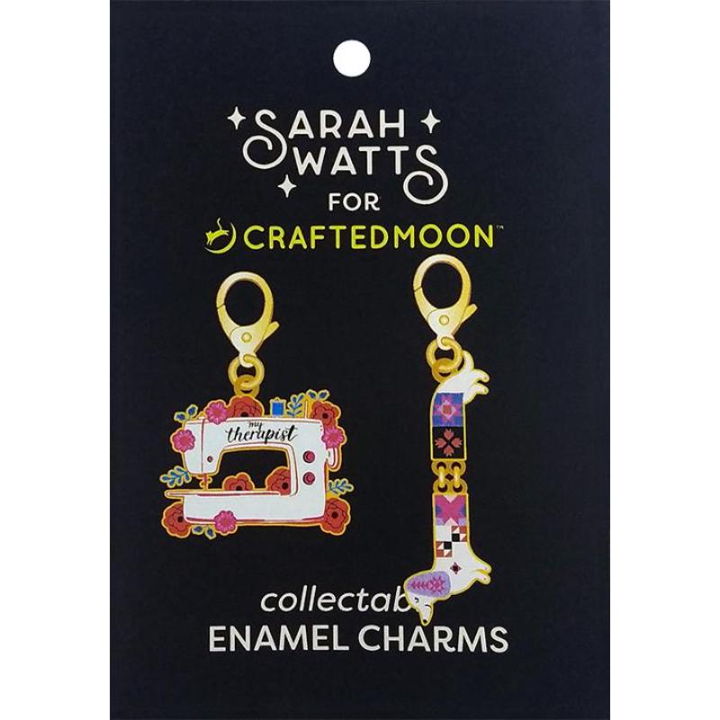 Sarah Watts for Crafted Moon collectable enamel charms on a black display card. The set includes a sewing machine charm decorated with flowers and the word 'therapist', and a colorful geometric animal charm shaped like a bird or fox.
