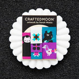Pack of socks with cartoon designs on a white stand against a black background, branded 'Craftedmoon' by Sarah Watts.