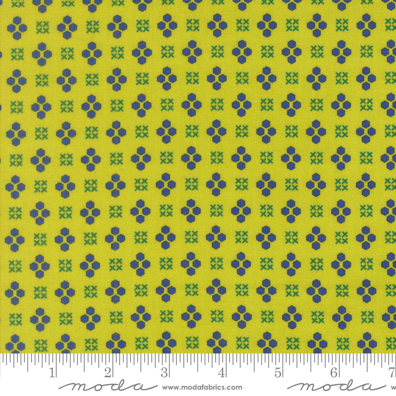 Fabric with blue and green geometric pattern on a yellow background, featuring a ruler at the bottom.