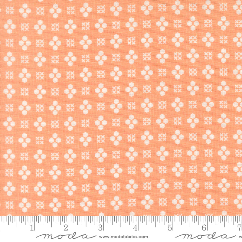 Patterned fabric with white geometric design on a peach background, featuring Moda label.
