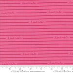 Pink fabric with 'handmade' text and Moda label, featuring a ruler for scale.