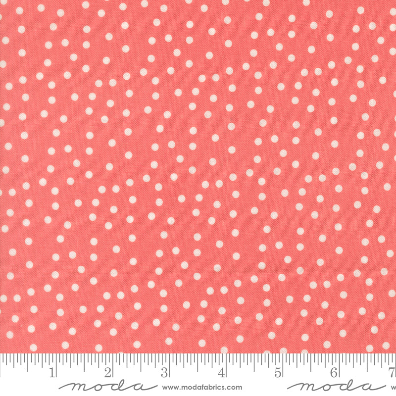 Coral fabric with white polka dots and a ruler at the bottom