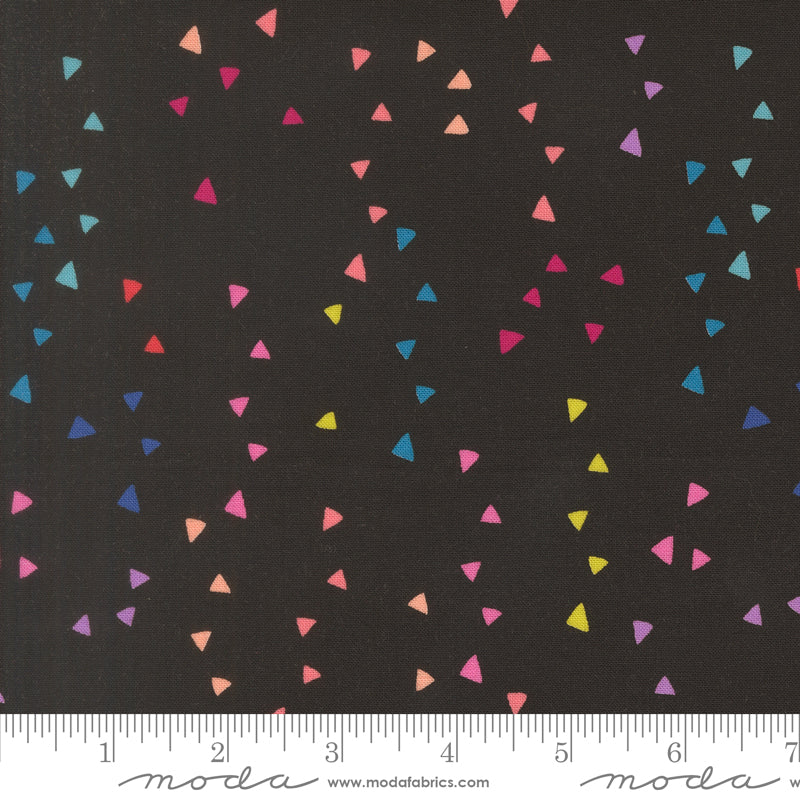 Colorful triangle pattern on black fabric with Moda label and ruler at the bottom.